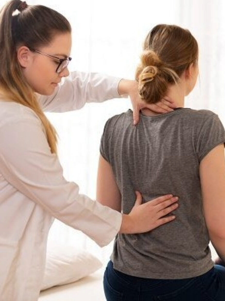 Doctor checking a patient’s spine during a chiropractic evaluation